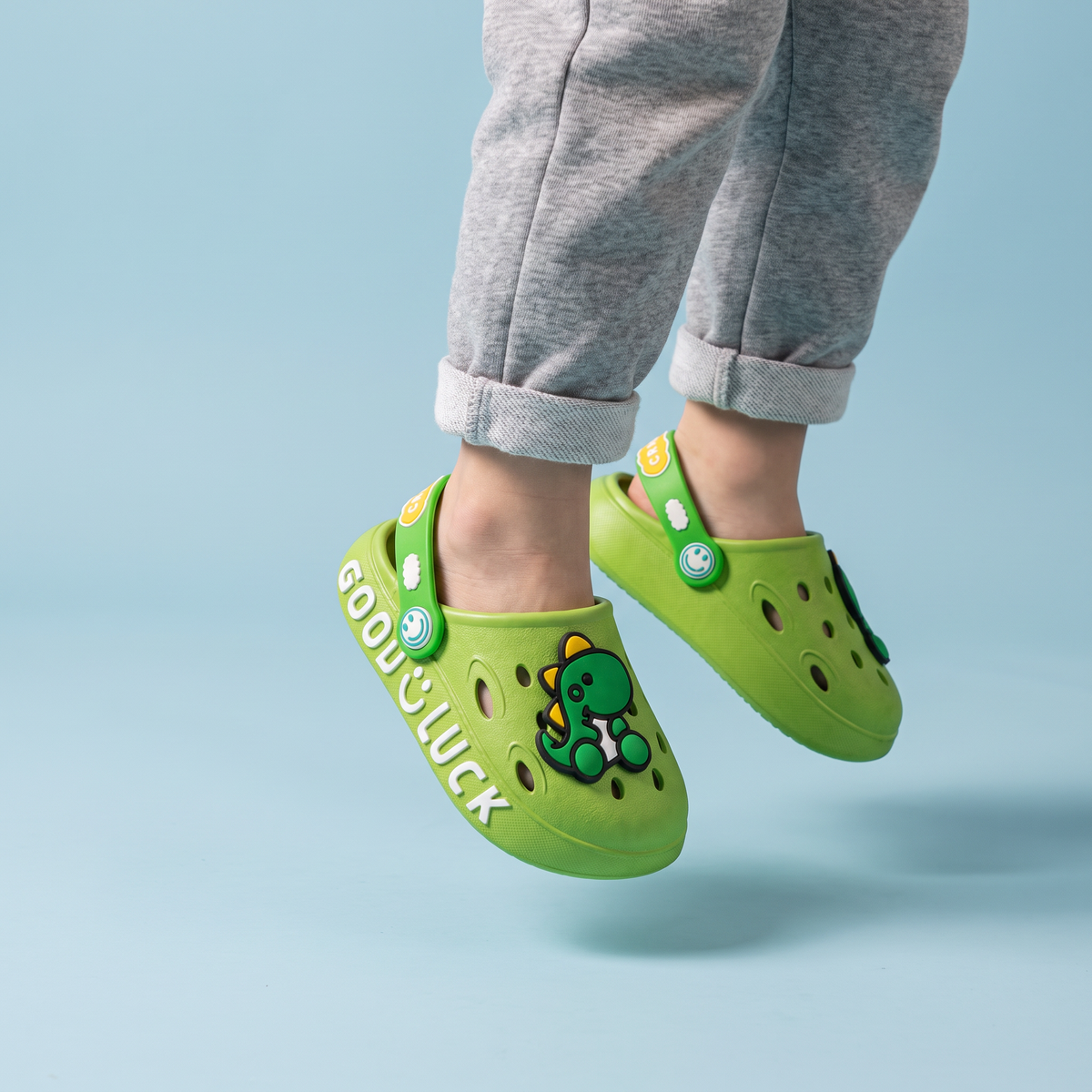 Pés de criança pulando com o Clog Infantil Dino verde