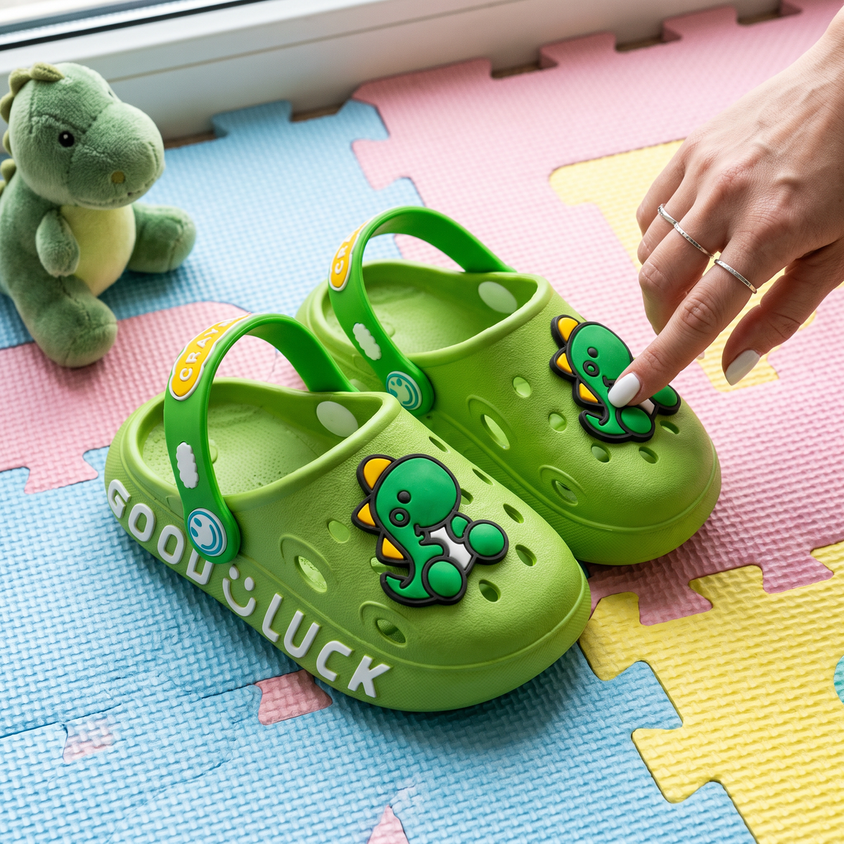Par do Clog Infantil Dino verde no tapete de brincar